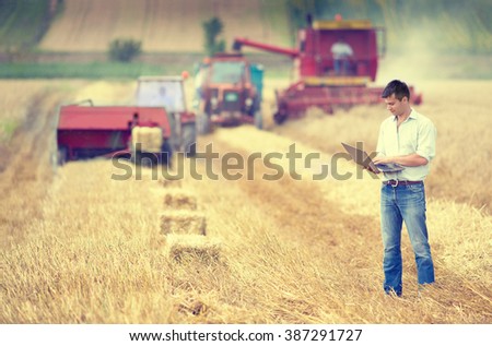 Young landowner with laptop supervising harvesting work
