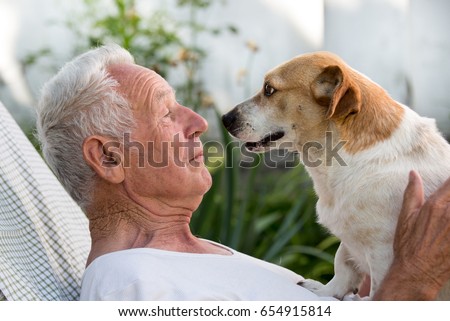 Old man resting in garden and cute dog climb on his chest and kissing him. Pet love concept