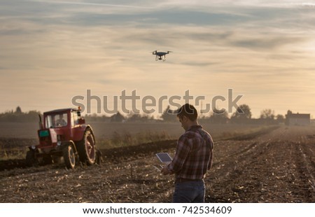 Attractive farmer navigating drone above farmland. High technology innovations for increasing productivity in agriculture