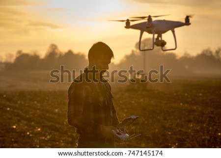 Attractive farmer navigating drone above farmland. High technology innovations for increasing productivity in agriculture