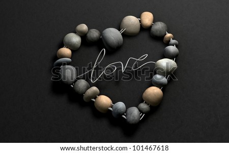 A handcrafted heart shape made out of wire and stones with the word  Love spelled out on a stone background