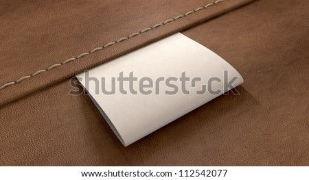 A white woven clothing label sewn into seamed brown leather