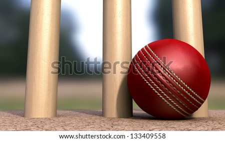 A red leather cricket ball lying on cracked soil at the base of wooden cricket wickets in the daytime