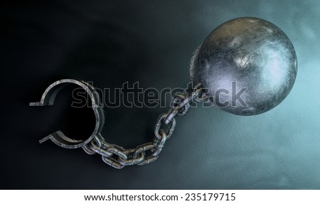 A vintage ball and chain with an open shackle on a dark backlit studio background