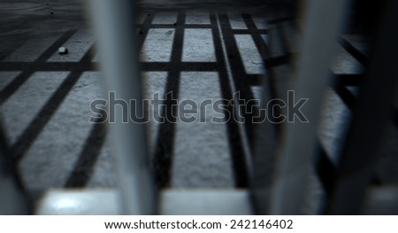 A closeup of view of a jail cells iron bars casting shadows on the prison floor with copy space