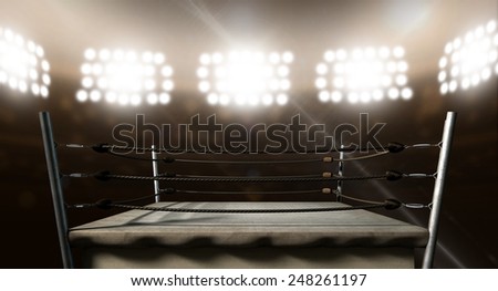 An old vintage boxing ring surrounded by ropes spotlit by floodlights in an arena setting at night