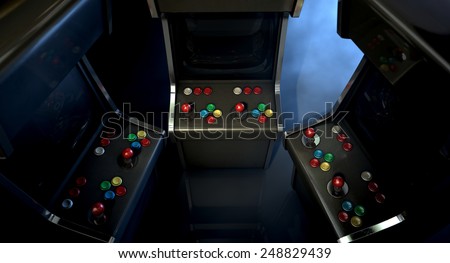 A group of vintage unbranded arcade games with a joysticks and buttons and a blank screen huddled facing each other on a dark ominous background with copy space