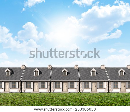 A row of stone cottages with chimneys and shutters on a blue sky and grass lawn background