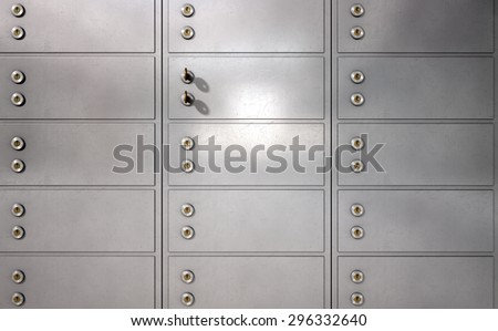 A closeup of a wall of closed metal safety deposit boxes and one with two keys inserted into it