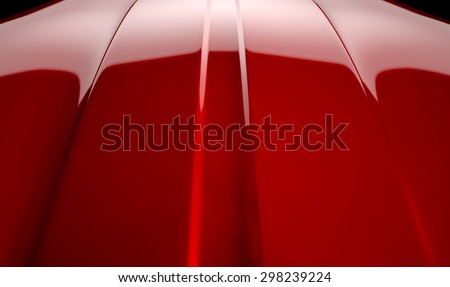 An abstract section of the contours of a cherry red automobile bonnet with dramatic lighting on a dark studio background