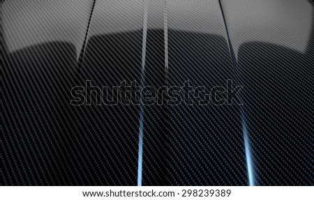 An abstract section of the contours of a carbon fiber automobile bonnet with dramatic lighting on a dark studio background