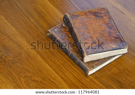 two leather covered old books on a wooden table
