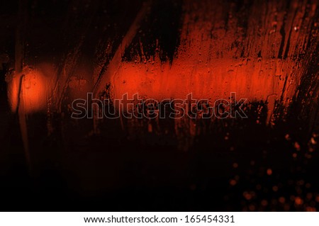 red light in the night seen through a wet window