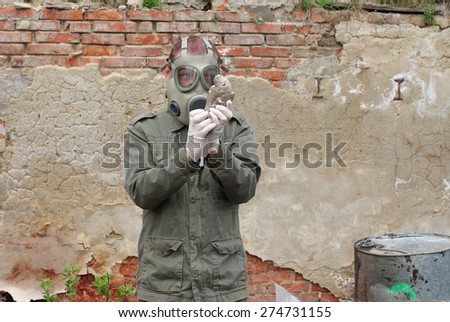 Man with gas mask and green military  clothes  explores  dead bird after chemical disaster.