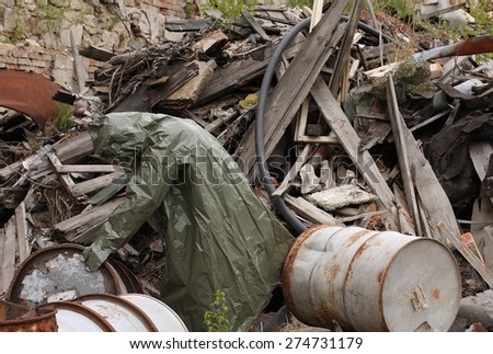 Man with gas mask and green military clothes  explores barrels  after chemical disaster.