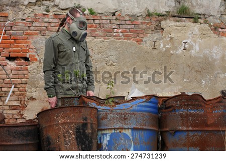 Man with gas mask and green military clothes  explores  small plant  after chemical disaster.