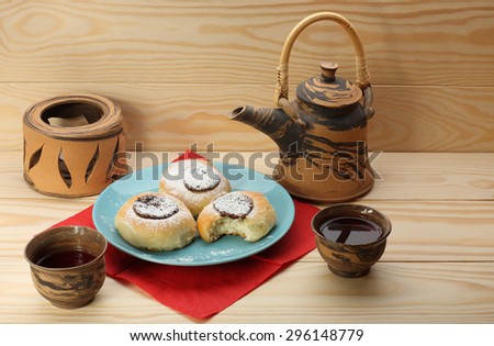 cottage cheese cakes  with jam on blue plate  and tea set on wooden table