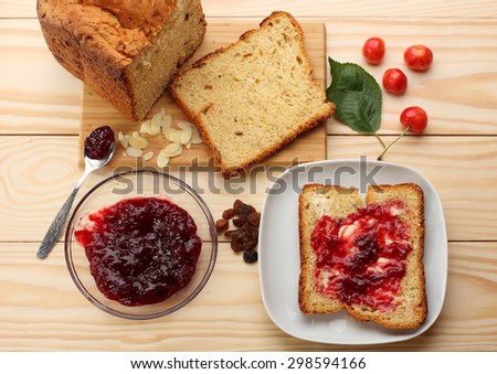 Sweet bread with raisins and almonds, butter and cherry jam.