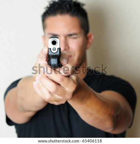 Image of young male pointing gun.  Focus on barrel of gun.