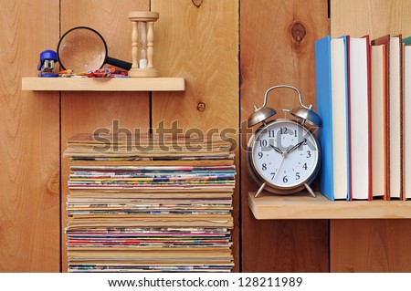 a pile of old magazine, clock, books and stationery on wooden shelf