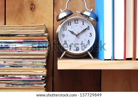 a pile of old magazine, clock, books on wooden shelf