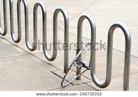 abandoned bike wheel locked with bike rack