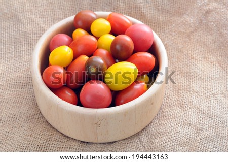 colorful grape tomato in wooden bowl on table