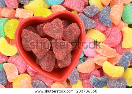 Valentine candy in heart shape bowl on colorful candy background