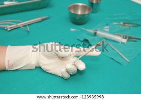 set of eye surgical instrument on sterile table with a hand of doctor grabbing a tool