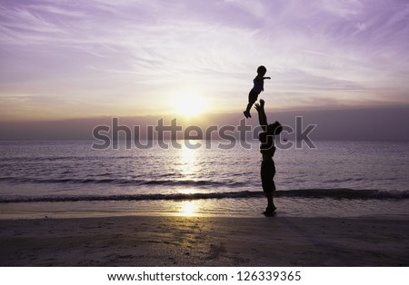 Happy family having fun on the beach,Father and son play on the Beach in sunrise silhouette shot