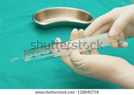 Doctor\'s hand holding Glass syringe in  sterile tray and glass bottle for tube feeding diet