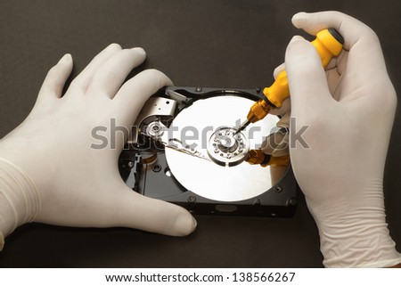 Hand with gloves repairs hard drive ,data recovery concept
