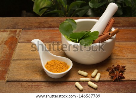 mortar and pestle with herb and pills on wood texture
