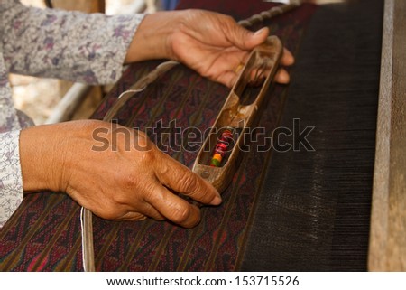 Woman working at Thai traditional loom with wooden bobbin