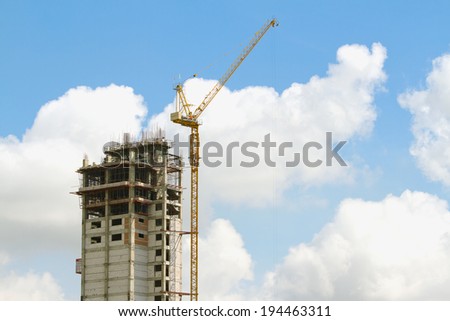 Working cranes inside with tall buildings under construction under a blue sky