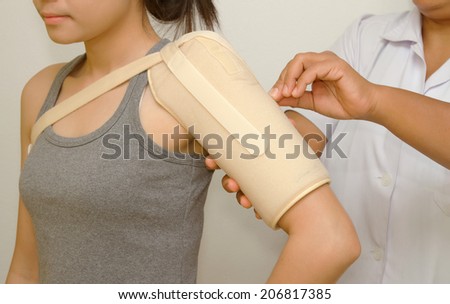 Physical therapist checking woman's  shoulder with shoulder support
