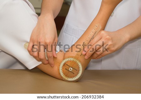 Physiotherapist measuring range of motion patients' elbow with goniometer