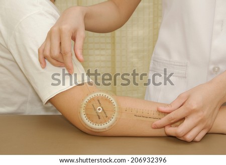 Physiotherapist measuring range of motion patients\' elbow with goniometer