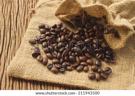 Coffee beans in coffee bag on wooden background