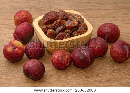 Dried plums and fresh plums on the wooden table