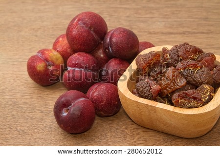 Dried plums and fresh plums on the wooden table