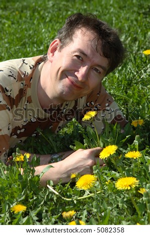 Man lie on green grass and hold flower