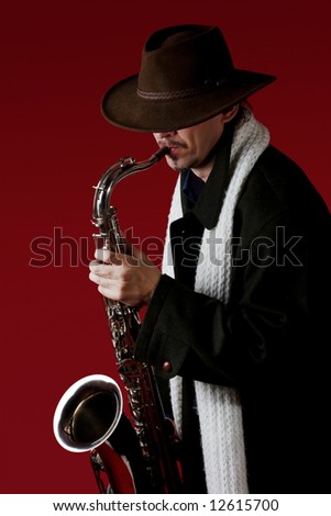 Man in coat with saxophone at red background