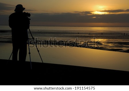 Silhouette of photographer at work during sunset