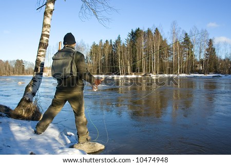 Man fly fishing in a river in winter, Finland