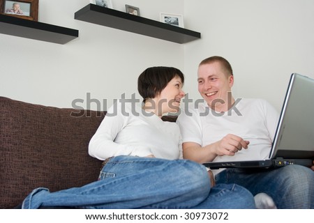 Attractive young couple using laptop on a sofa