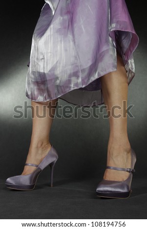 Woman wearing lilac satin dress and shoes over greey