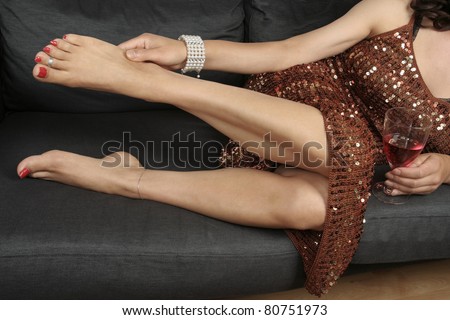 Beautiful female legs massaging aching feet wearing party dress relaxing