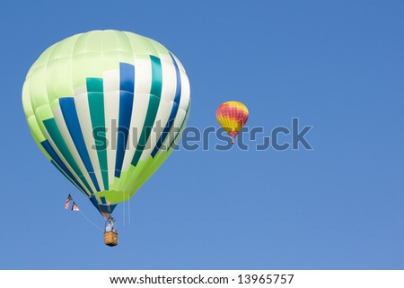 2 hot air balloons hang in the beautiful blue sky