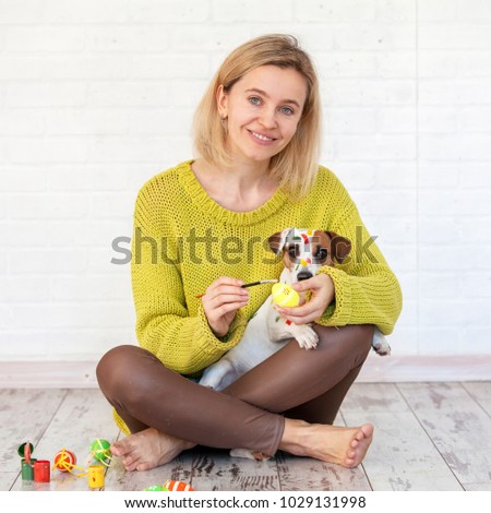Woman and dog color Easter eggs. Female with pet painting